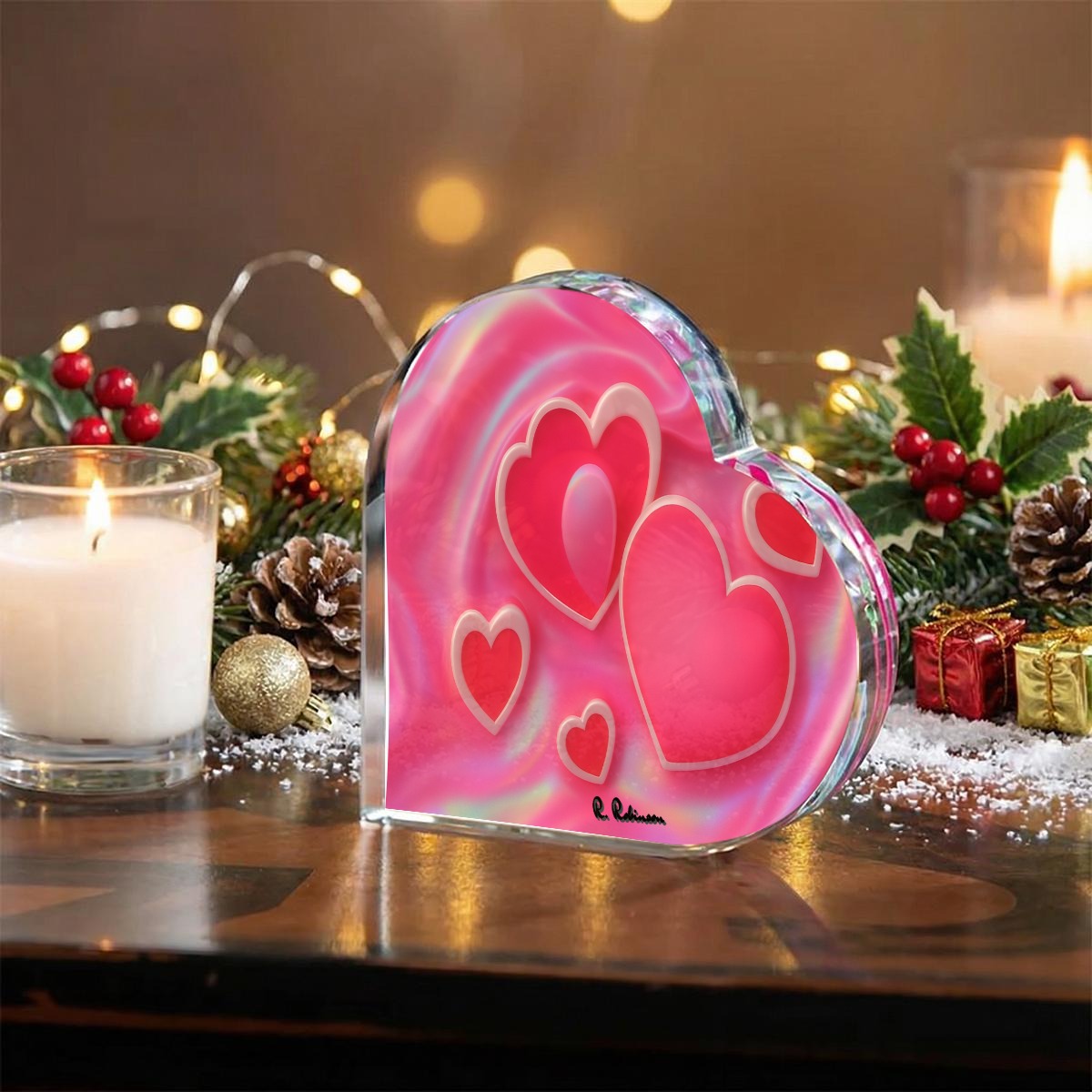 Heart-shaped pink glass ornament with a candle and Christmas decorations in the background