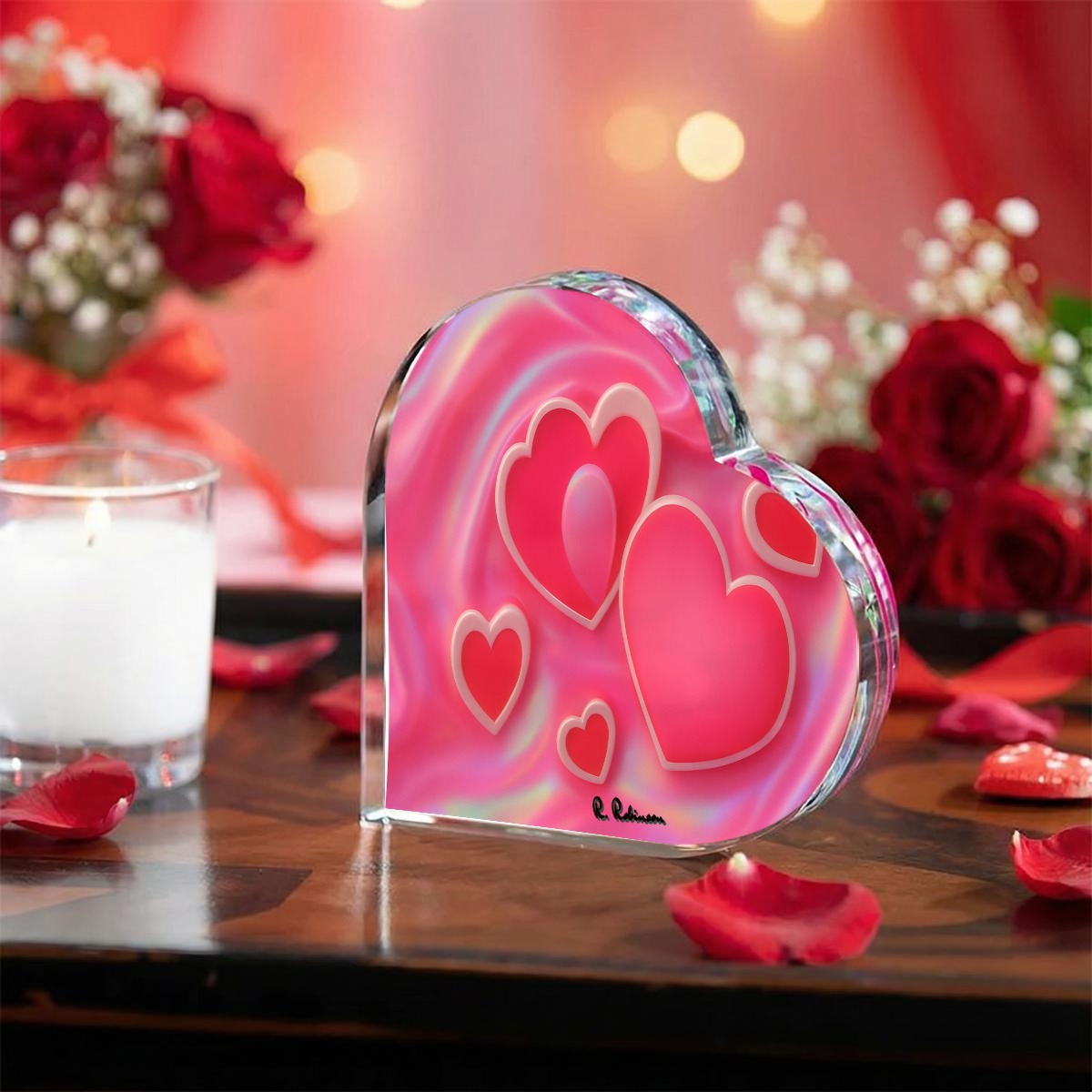 Heart-shaped glass ornament with pink hearts on a wooden surface with flowers and a candle in the background