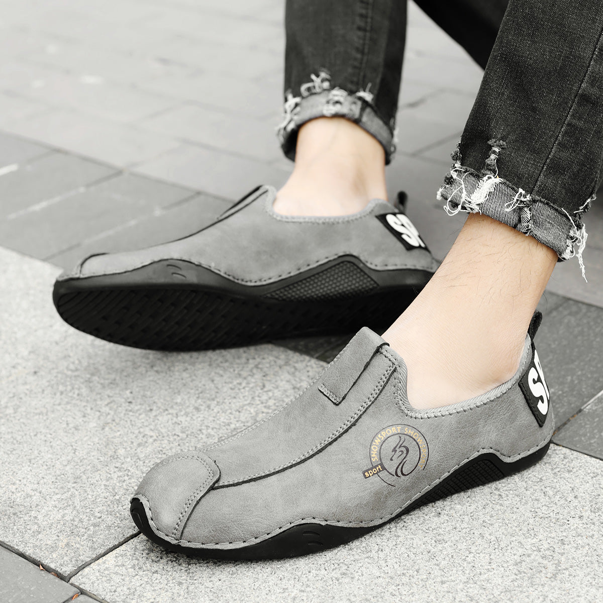 Gray loafers worn by a person on a pavement