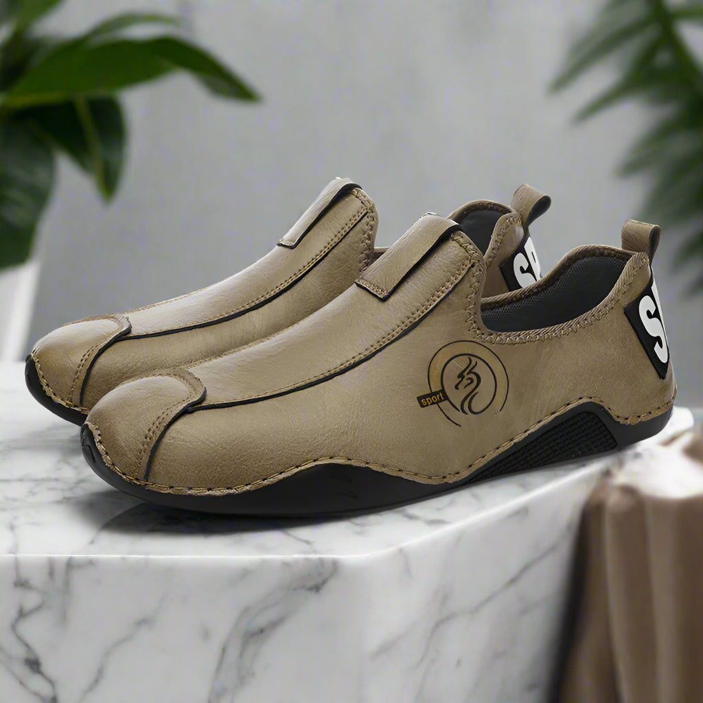 Pair of tan slip-on shoes with black soles on a white background