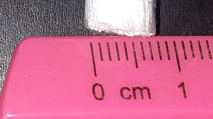 Pink ruler with measurement markings on a black background